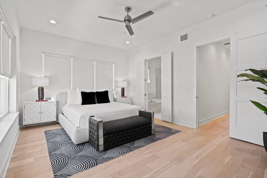 Blonde wood flooring and white walls define this well-lit, contemporary bedroom, featuring an ensuite bath. Blonde wood flooring and white walls define this well-lit, contemporary bedroom, featuring an ensuite bath.