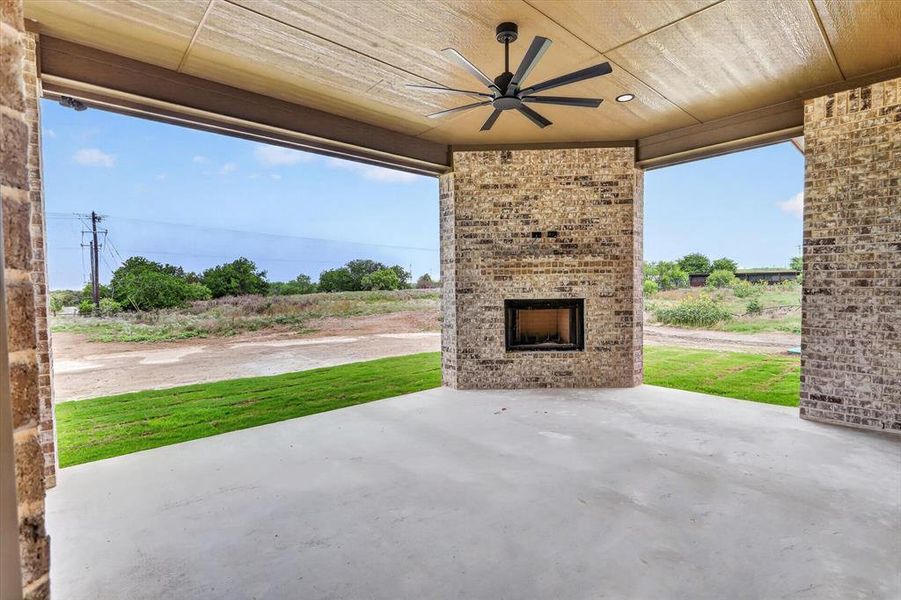 Covered outdoor patio featuring a brick fireplace with an integrated firebox, a ceiling fan, recessed lighting, and a concrete floor Covered outdoor patio featuring a brick fireplace with an integrated firebox, a ceiling fan, recessed lighting, and a concrete floor