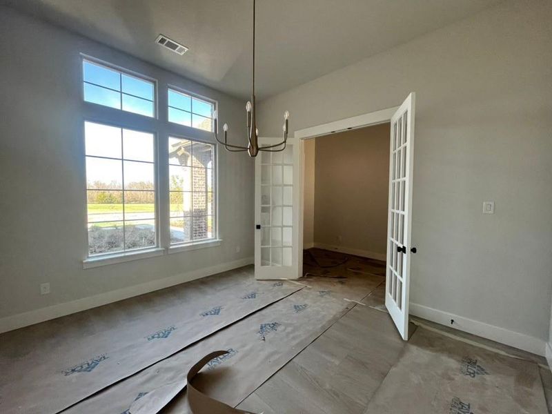 Unfurnished dining area featuring french doors and hanging lights