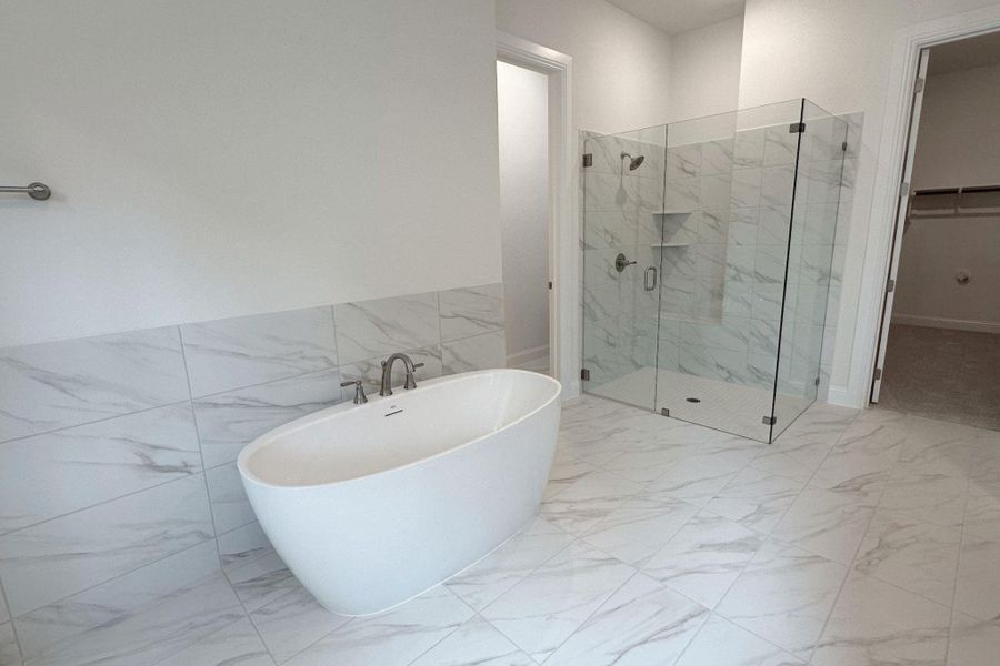 A deep soaking tub and tiled walk-in shower provide a luxurious bathing experience.