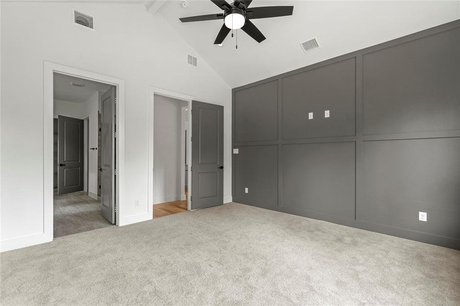 Unfurnished bedroom featuring carpet, beam ceiling, high vaulted ceiling, connected bathroom, and a ceiling fan