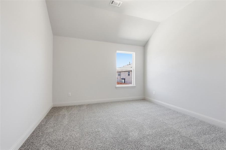 Carpeted empty room with vaulted ceiling and baseboards