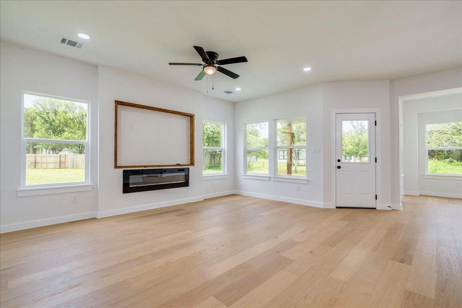 Bright, living area features light wood flooring and an abundance of light