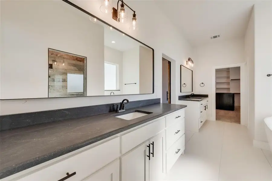 Dual vanity bathroom featuring an expansive countertop, undermount sinks, and white cabinetry