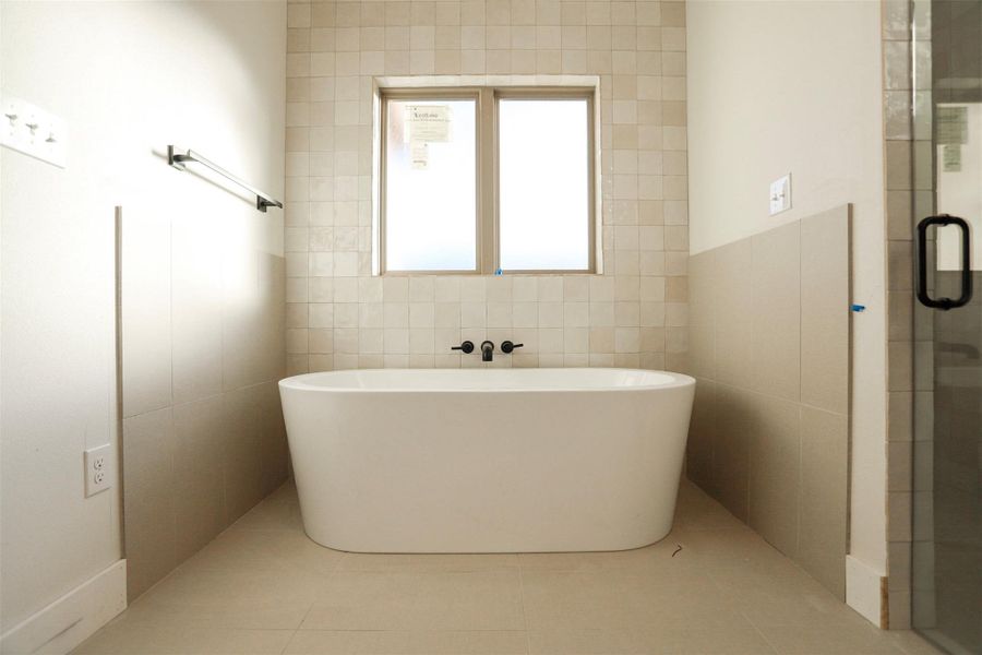 Bathroom featuring tile walls, a shower stall, a soaking tub, and light tile patterned floors