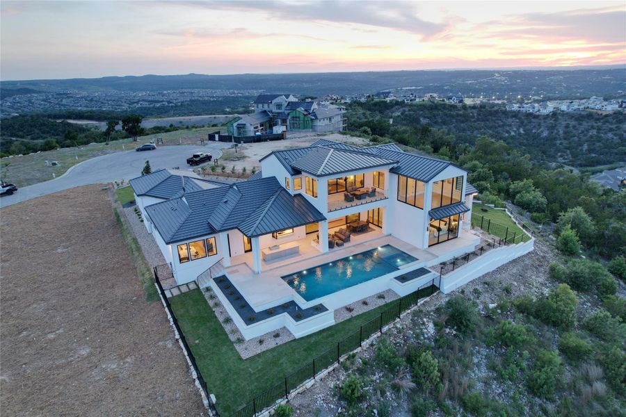 Contemporary multi-level residence featuring a white exterior, dark metal roofing, and multiple balconies Contemporary multi-level residence featuring a white exterior, dark metal roofing, and multiple balconies