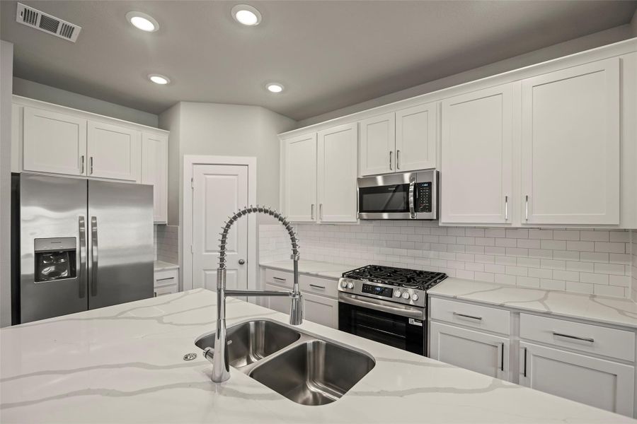 Sleek and functional kitchen with gleaming countertops, abundant cabinetry, and a walk-in pantry. Sleek and functional kitchen with gleaming countertops, abundant cabinetry, and a walk-in pantry.