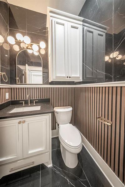 Bathroom featuring vanity and dark marble finish floors Bathroom featuring vanity and dark marble finish floors