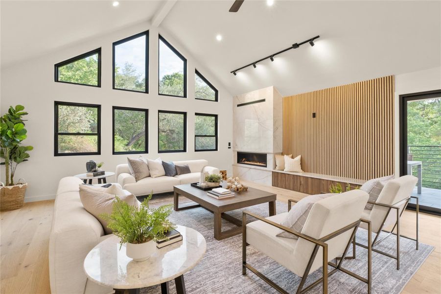 Living area with beam ceiling, light wood-style flooring, a premium fireplace, high vaulted ceiling, and baseboards