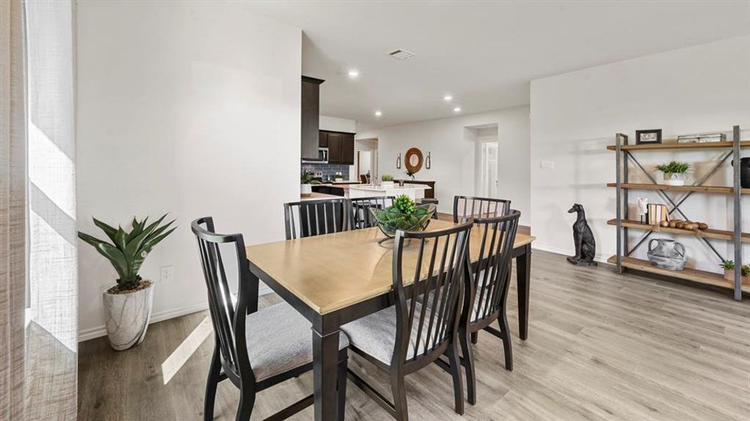The dining area features light wood flooring and recessed lighting
