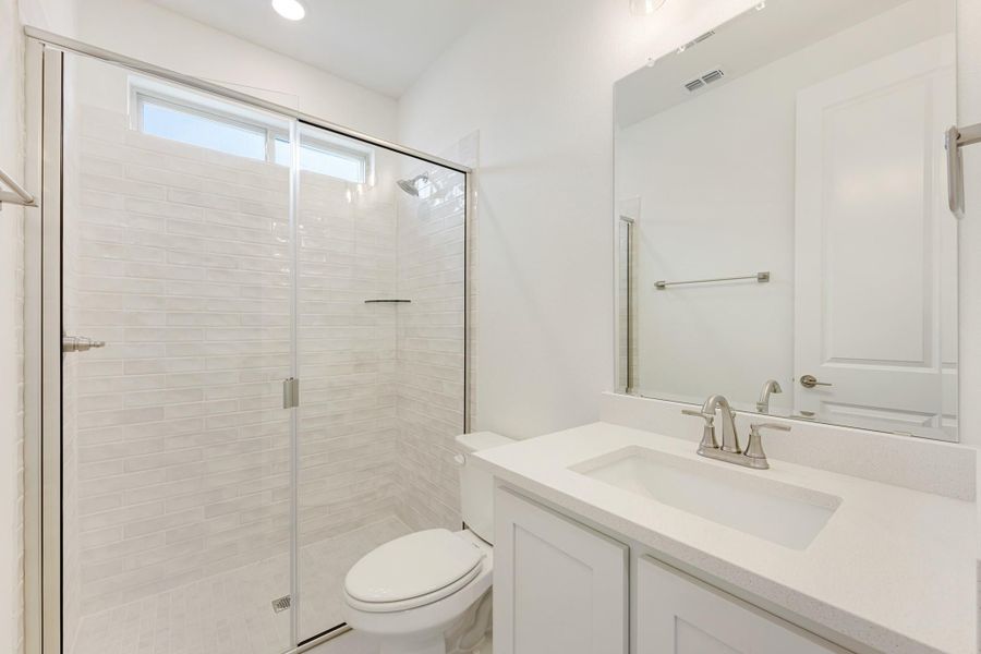 Bathroom with glass-enclosed tile shower, white vanity with quartz countertop, and large mirror Bathroom with glass-enclosed tile shower, white vanity with quartz countertop, and large mirror