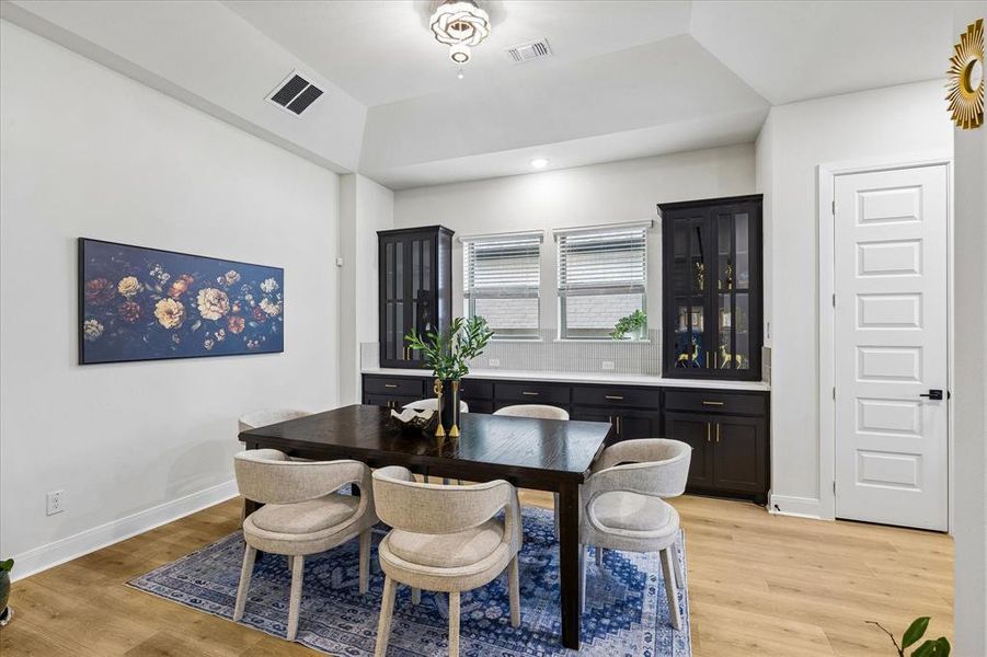 Dining area featuring wood-finish flooring and a tray ceiling with a contemporary light fixture Dining area featuring wood-finish flooring and a tray ceiling with a contemporary light fixture
