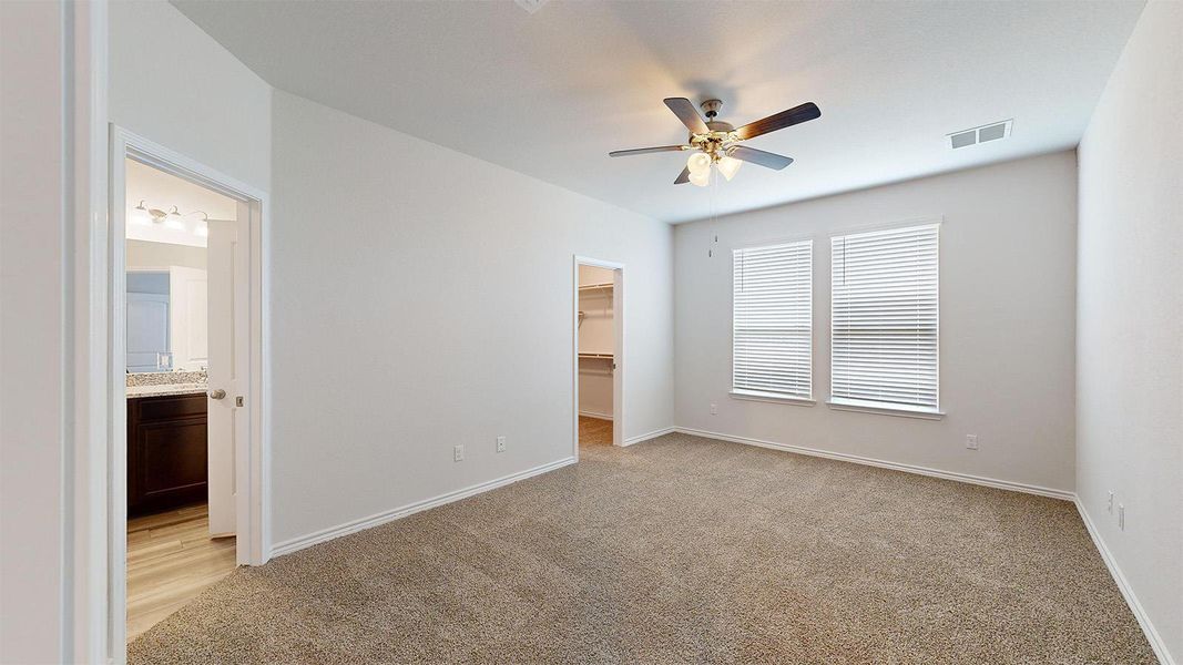 Unfurnished bedroom with a spacious closet, light carpet, and a ceiling fan