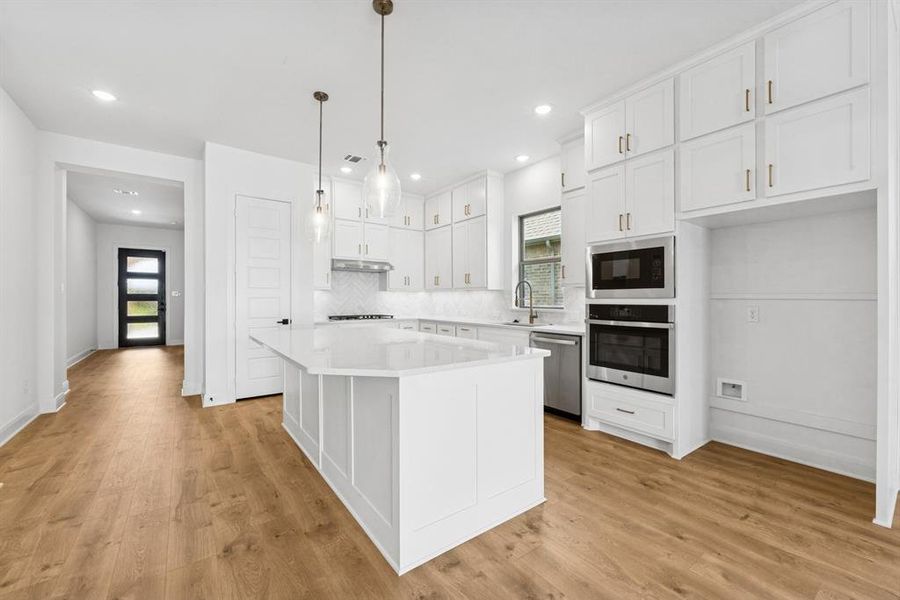 Kitchen with white cabinets, stainless steel appliances, a center island, and healthy amount of natural light Kitchen with white cabinets, stainless steel appliances, a center island, and healthy amount of natural light