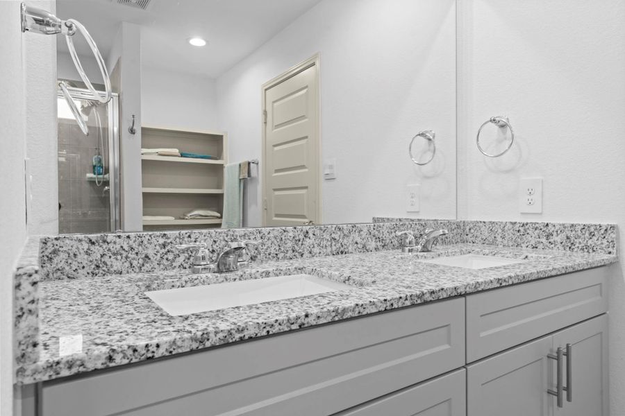 Dual vanity area in the primary bathroom with sleek granite countertops, undermount sinks, modern fixtures, and ample storage space — perfect for busy mornings or relaxing evening routines. Dual vanity area in the primary bathroom with sleek granite countertops, undermount sinks, modern fixtures, and ample storage space — perfect for busy mornings or relaxing evening routines.