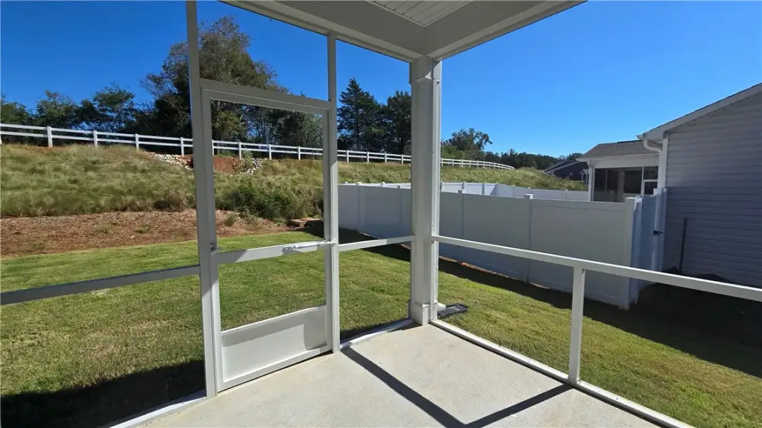 An inviting screened porch overlooks a grassy, fen