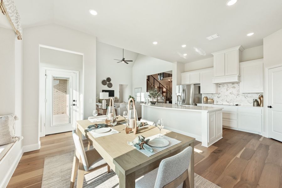 Open-concept dining area and kitchen with white cabinets, large island, and hardwood floors