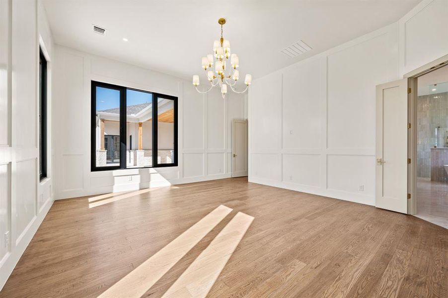 Empty room with a decorative wall, light wood-type flooring, and hanging lights