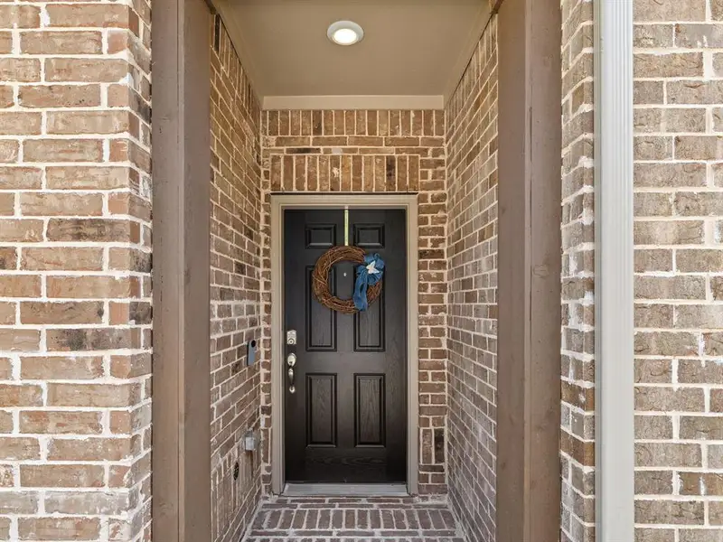 A deep, covered front porch shields the main entrance from the elements and provides a welcoming transition into the home.