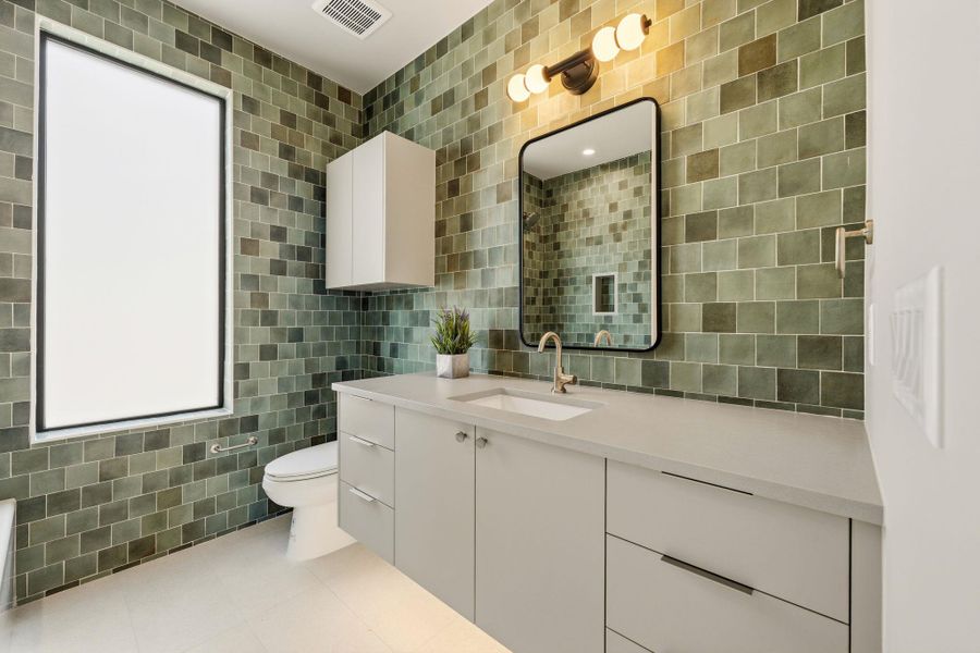 Sleek vanity with ample storage complements the unique tiled walls in this contemporary bathroom. Sleek vanity with ample storage complements the unique tiled walls in this contemporary bathroom.