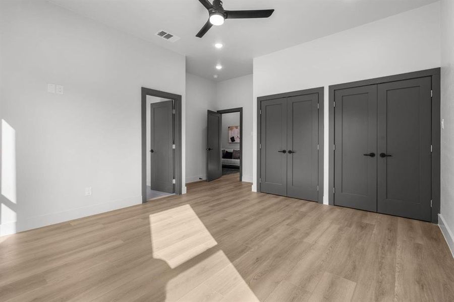 Unfurnished bedroom with multiple closets, light wood finished floors, a ceiling fan, and recessed lighting