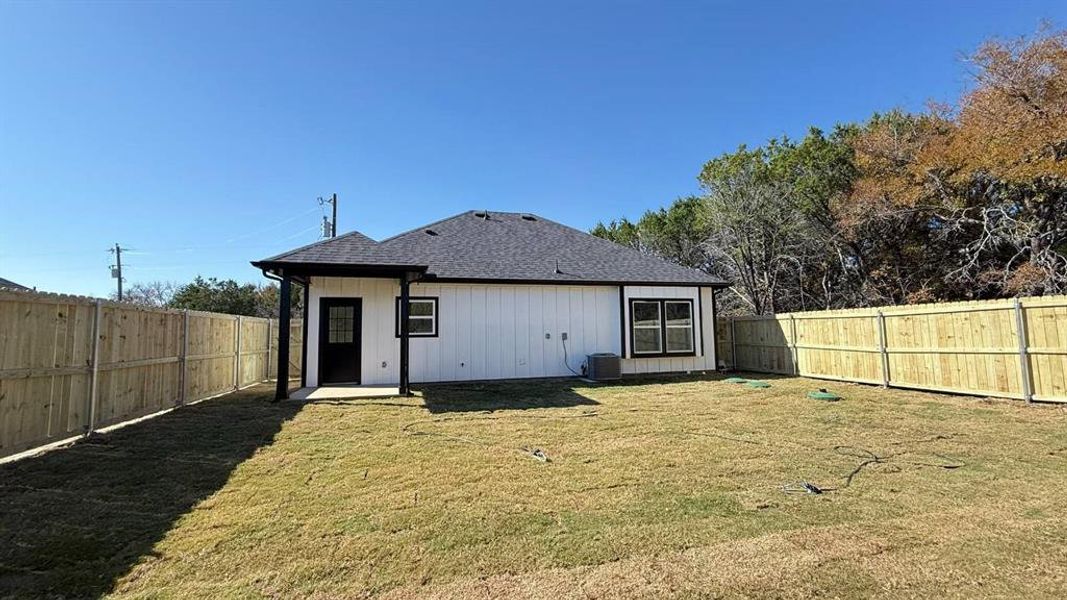 Rear view of property featuring a patio area, a fenced backyard, and a shingled roof