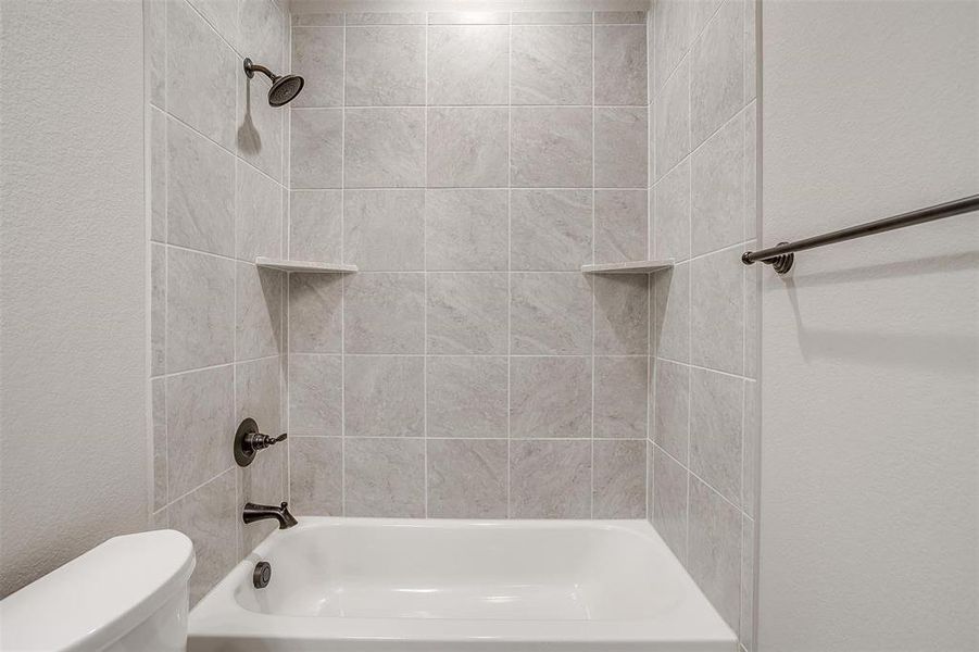 Bathroom featuring toilet and tiled shower / bath combo