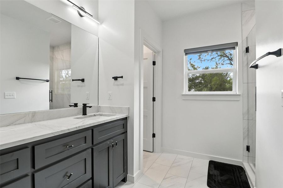 Bathroom featuring vanity, a stall shower, and light marble finish flooring