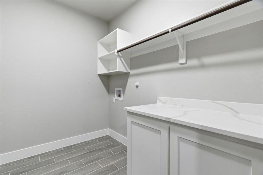 Washroom with hookup for a washing machine, wood finish floors, and cabinet space