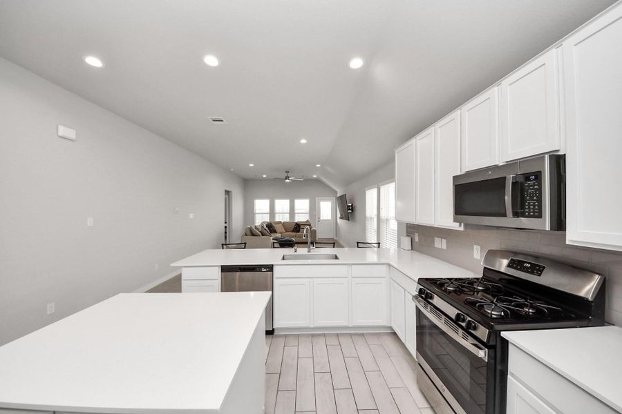 Enjoy an open sightline from the kitchen into the dining and living areas, with the island and sink positioned to face the main gathering space for easy interaction while cooking.