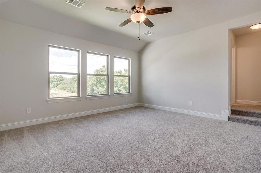 Carpeted empty room with vaulted ceiling and ceiling fan