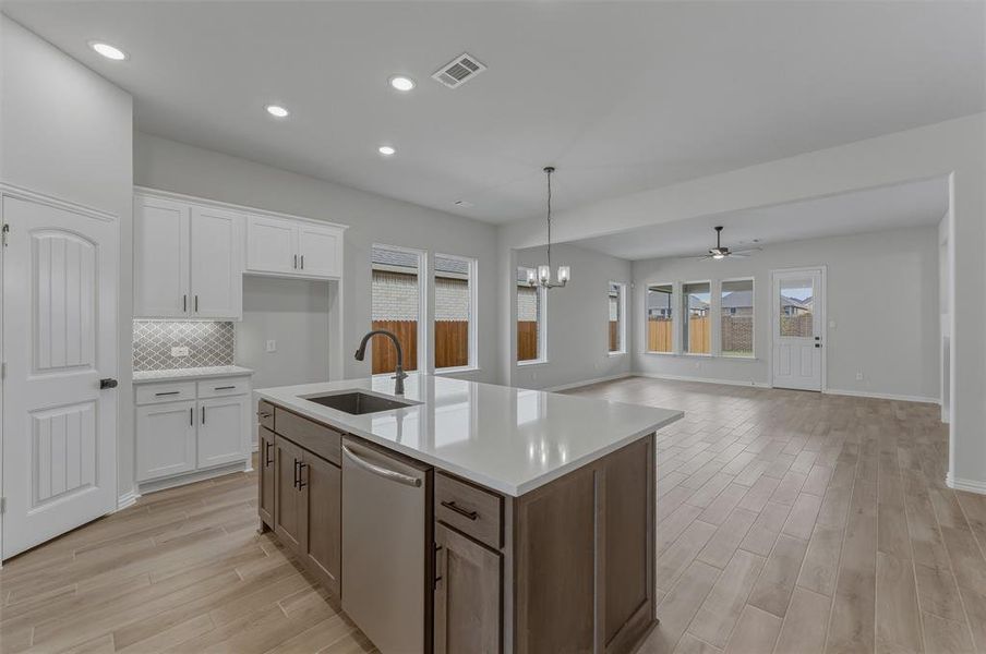 Modern kitchen island with an integrated sink and dishwasher, featuring a light countertop and wood-finish cabinetry