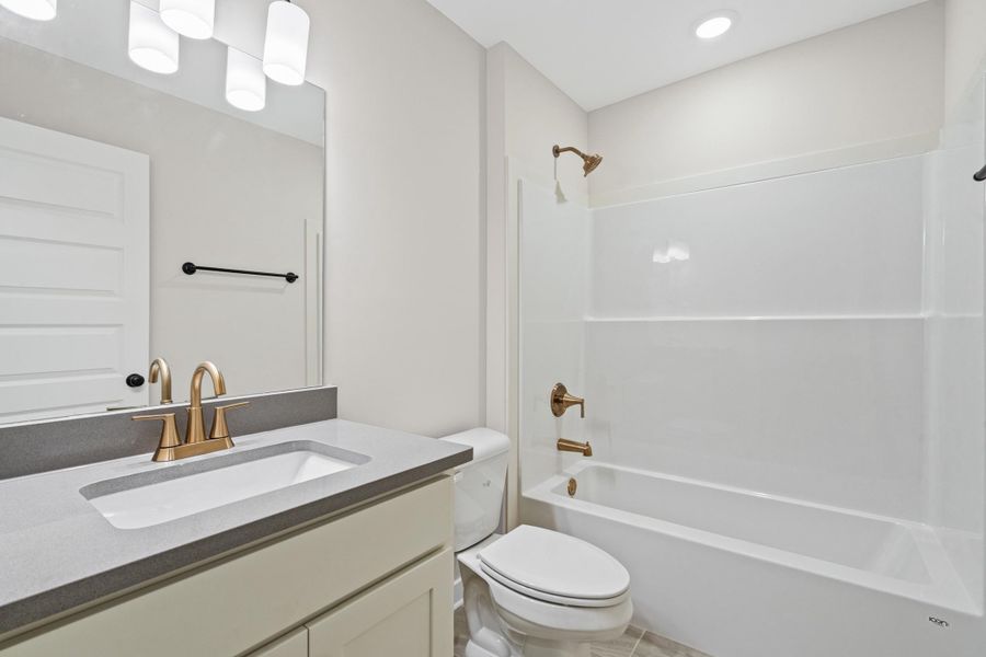 Bathroom featuring a vanity with an integrated sink, a gray countertop, and a brass-finish faucet Bathroom featuring a vanity with an integrated sink, a gray countertop, and a brass-finish faucet