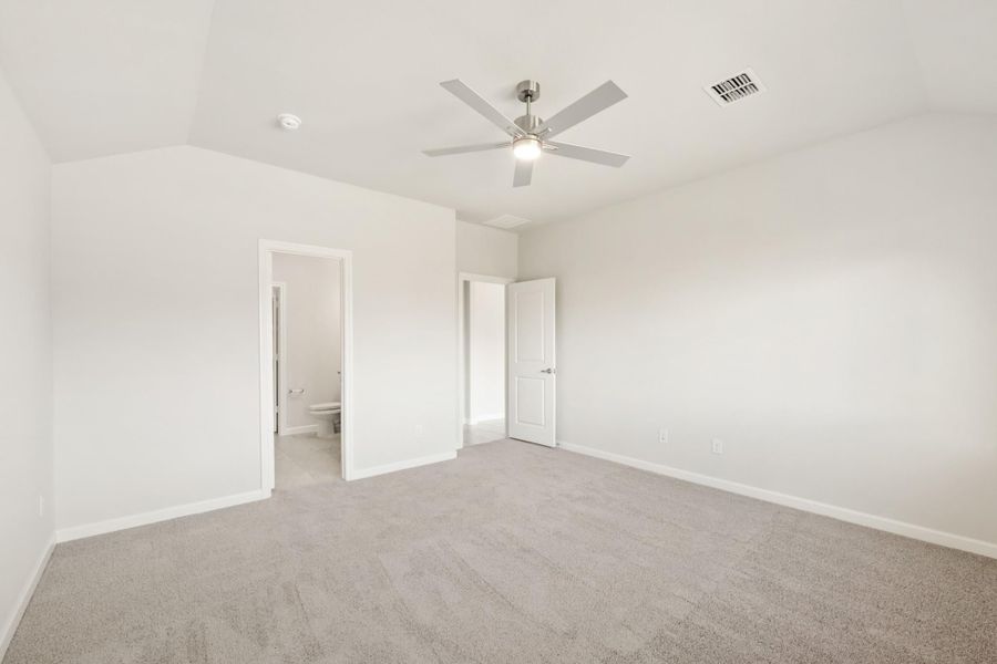 Empty bedroom with gray carpet, ceiling fan, and doors leading to bathroom and closet Empty bedroom with gray carpet, ceiling fan, and doors leading to bathroom and closet