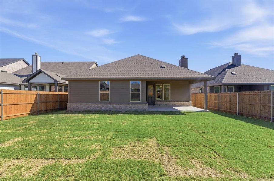 Back of property with a shingled roof, a patio area, a fenced backyard, and brick siding