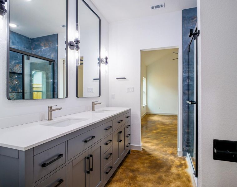 Full bath with finished concrete flooring, a stall shower, double vanity, and baseboards