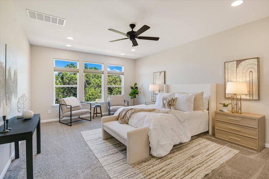 The spacious primary bedroom features a sitting area that looks out to a protected greenbelt view!