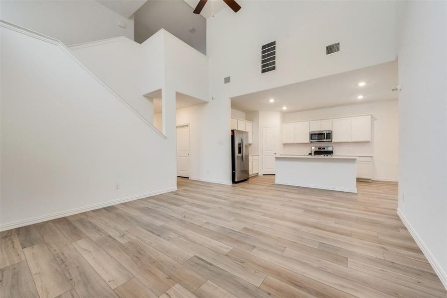 Unfurnished living room with high vaulted ceiling, ceiling fan, and light hardwood / wood-style floors