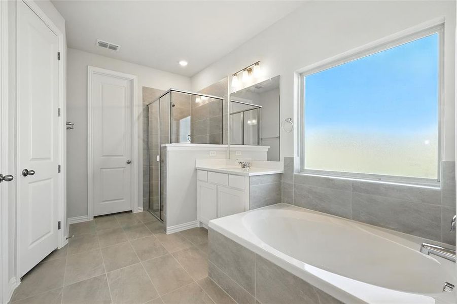 Full bath with vanity, a shower stall, a bath, and light tile patterned floors Full bath with vanity, a shower stall, a bath, and light tile patterned floors