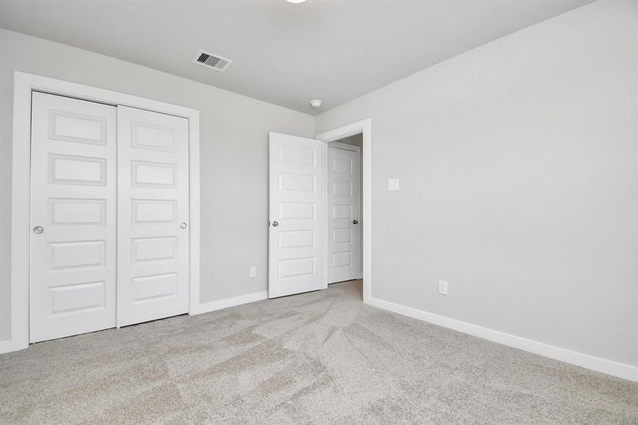 Generously sized secondary bedrooms, complete with spacious closets and soft, inviting carpeting.  Sample photo of completed home with similar plan. As built color and selections may vary.