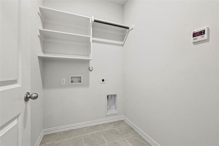 Laundry area with hookup for a washing machine, electric dryer hookup, light tile patterned floors, and hookup for a gas dryer