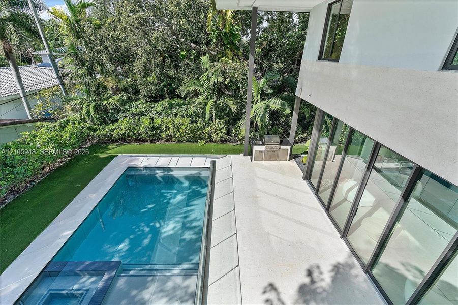 Outdoor area featuring a swimming pool, integrated spa, built-in outdoor kitchen, expansive patio, and synthetic turf lawn