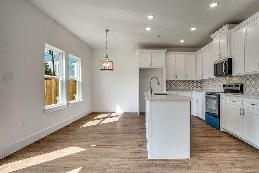 Kitchen featuring appliances with stainless steel finishes, white cabinets, decorative backsplash, recessed lighting, and a kitchen island with sink Kitchen featuring appliances with stainless steel finishes, white cabinets, decorative backsplash, recessed lighting, and a kitchen island with sink