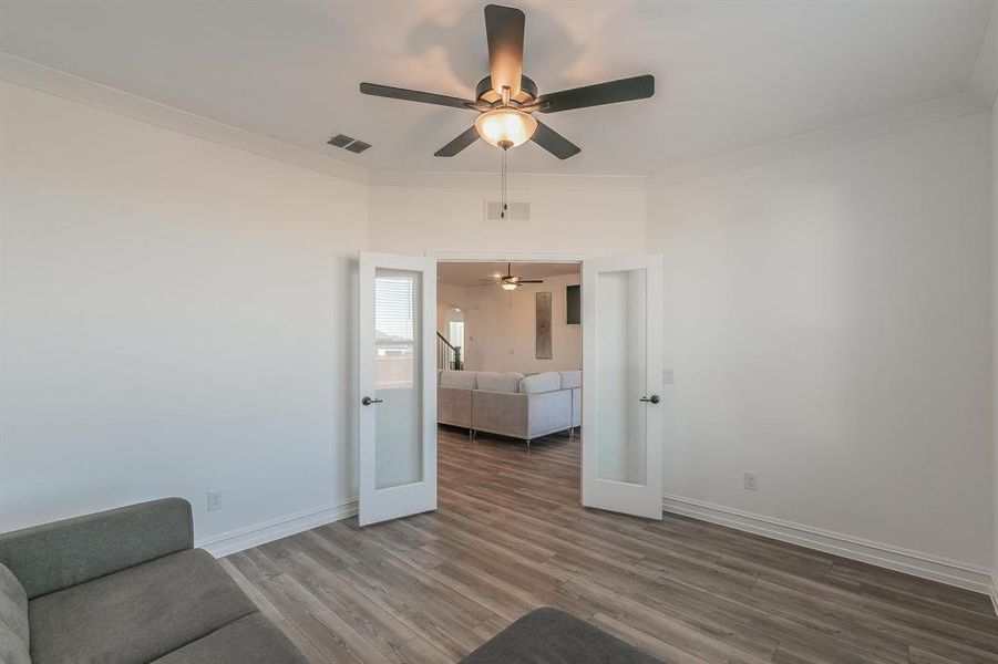 Unfurnished room featuring ceiling fan, french doors, crown molding, and hardwood / wood-style flooring