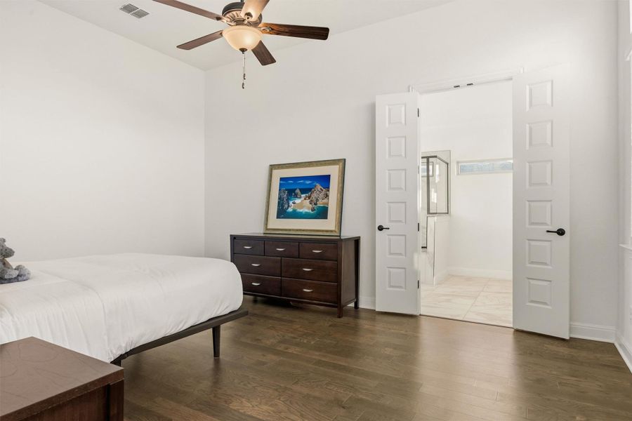 Bedroom featuring dark wood-type flooring, a ceiling fan, and ensuite bathroom