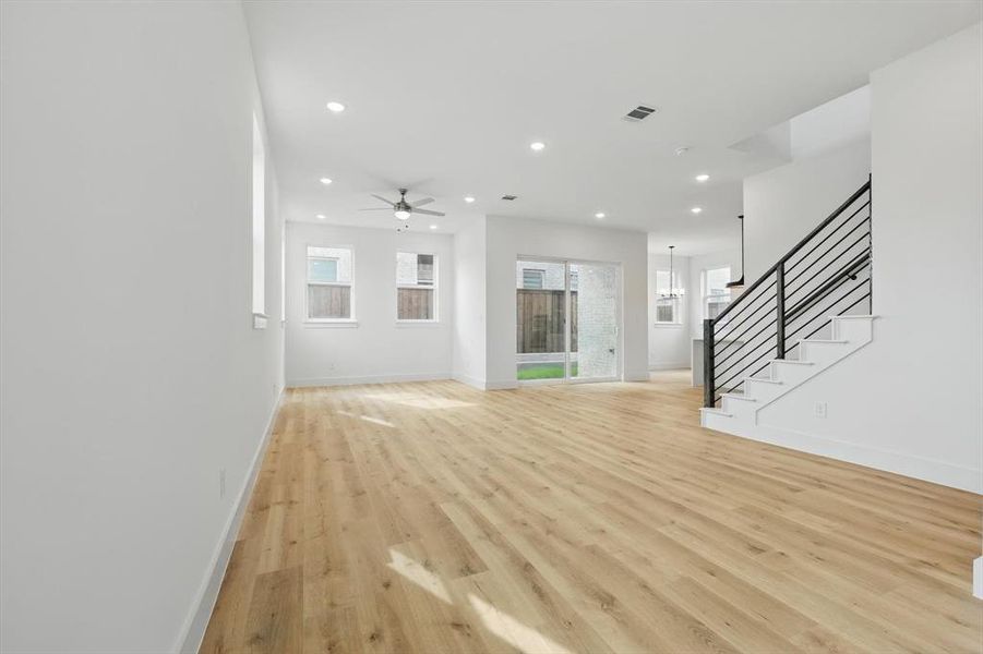 Unfurnished living room with light wood finished floors, recessed lighting, stairway, ceiling fan, and baseboards