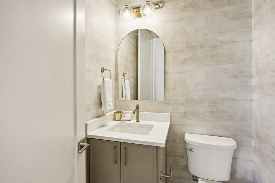 The stylish first floor powder bath adds another layer of convenience for guests with a sleek vanity, arched mirror and custom wallpaper. It is an added bonus downstairs, with a separate full bathroom located in the 5th bedroom/study.