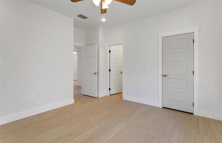 Spacious interior room featuring light wood-finish flooring, crisp white walls, and modern paneled doors with brushed nickel hardware Spacious interior room featuring light wood-finish flooring, crisp white walls, and modern paneled doors with brushed nickel hardware
