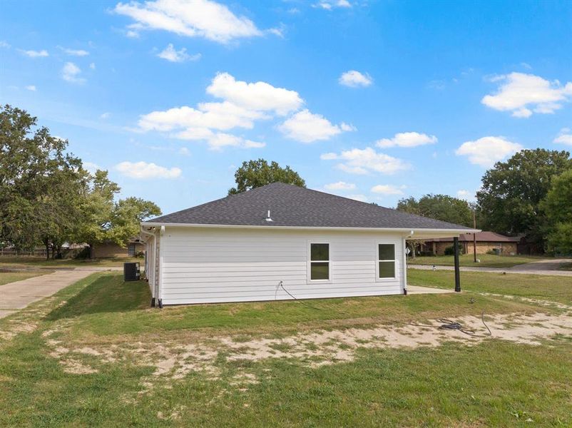 View of property exterior with a yard and roof with shingles
