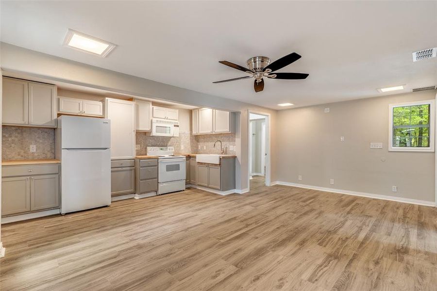 Kitchen featuring white appliances, ceiling fan, backsplash, light wood-style floors, and gray cabinets Kitchen featuring white appliances, ceiling fan, backsplash, light wood-style floors, and gray cabinets